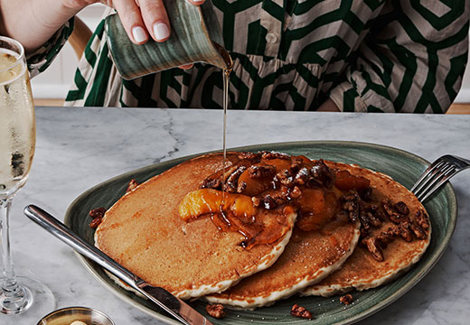 woman pouring syrup onto pancakes